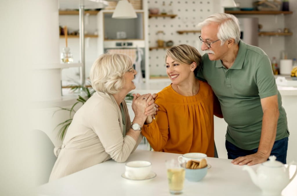 Three generations smiling and holding hands at a kitchen table