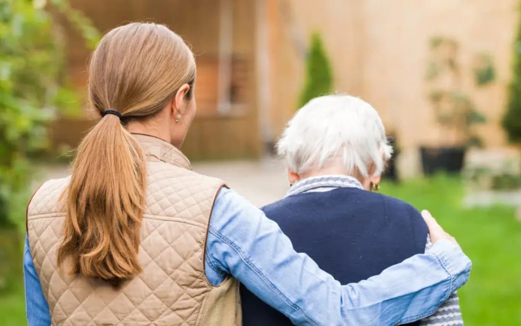 A woman puts her arm around an elderly man's shoulders