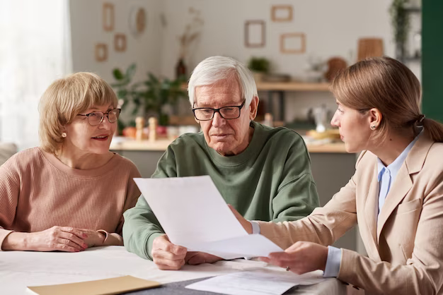 Senior couple sitting at table and discussing documents with agent